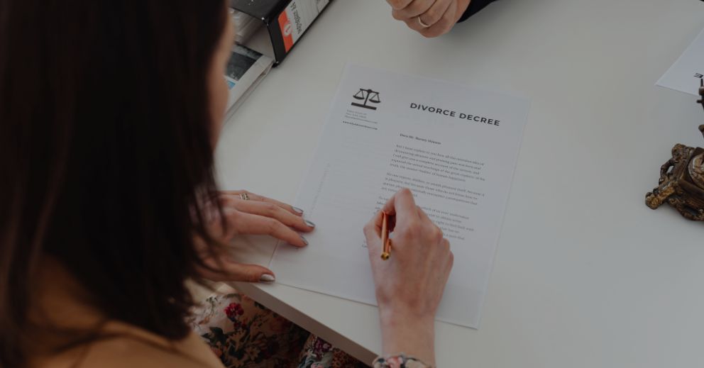 A woman signing a document at a desk, related to property settlement in family law in Brisbane.