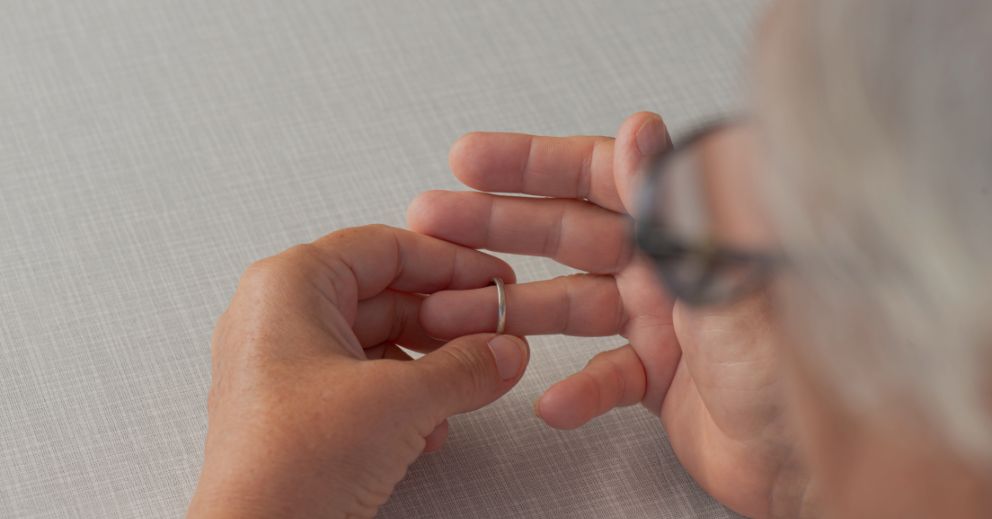 Person removing a wedding ring from their finger, seen from above.