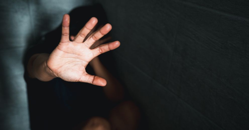 Person sitting with face hidden, shielding themselves—lawyers for domestic violence can help.