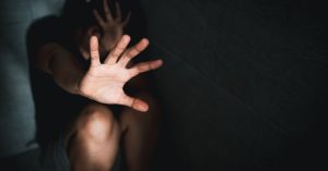 Person shielding themselves, highlighting domestic violence vs family law abuse issues.