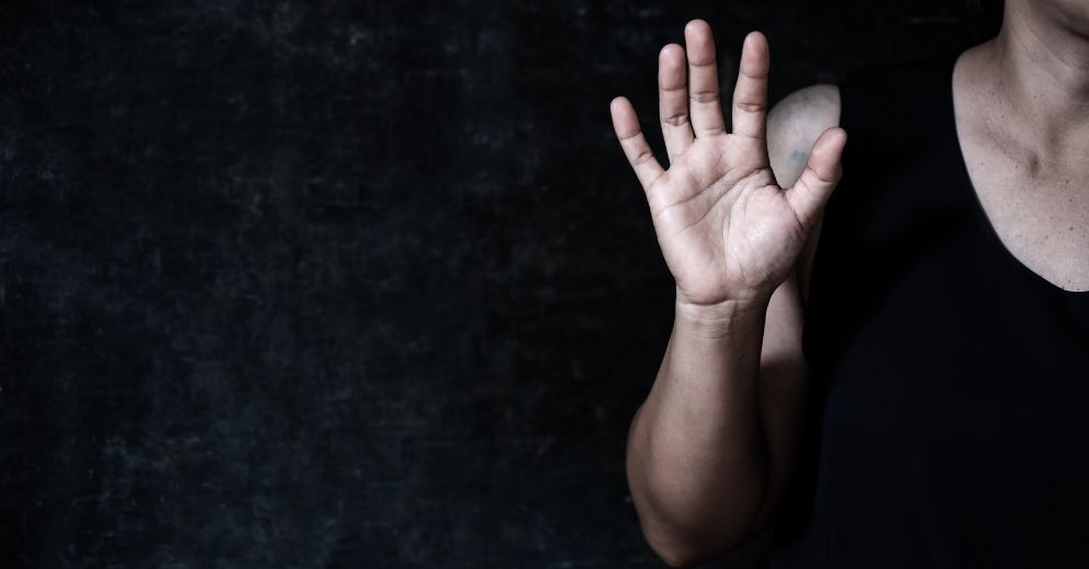 Person in a black top holding up one hand, symbolizing the Domestic Violence Legal Process Timeline.