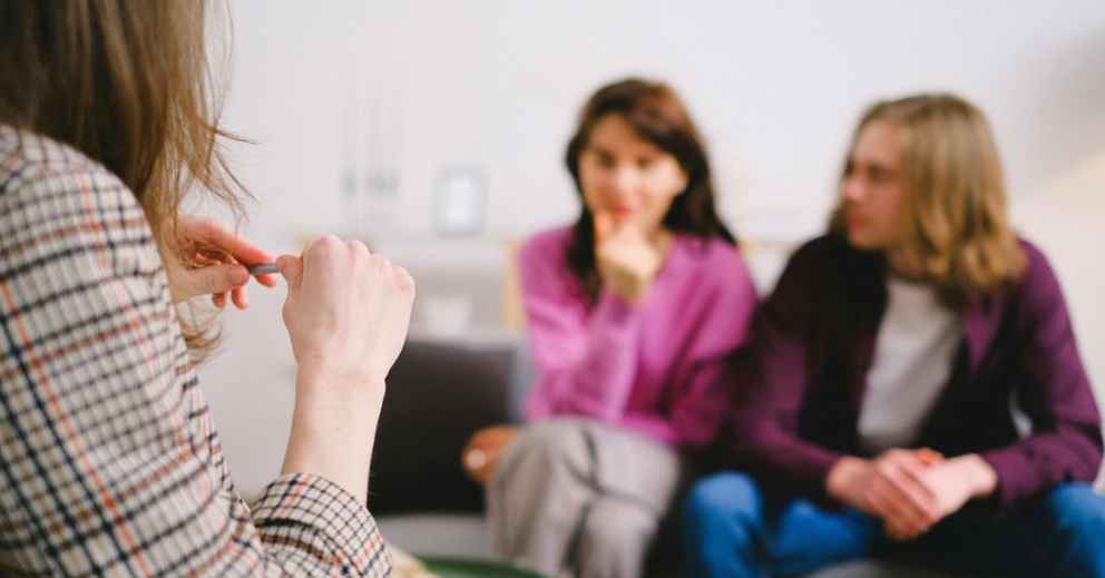 Three people sit indoors; two listen closely, perhaps consulting the Best Family Lawyer Brisbane.