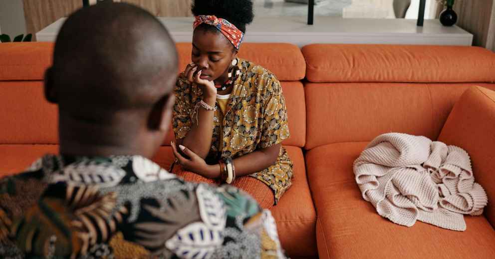 Two people sit on an orange sofa, reflecting on their date of separation.