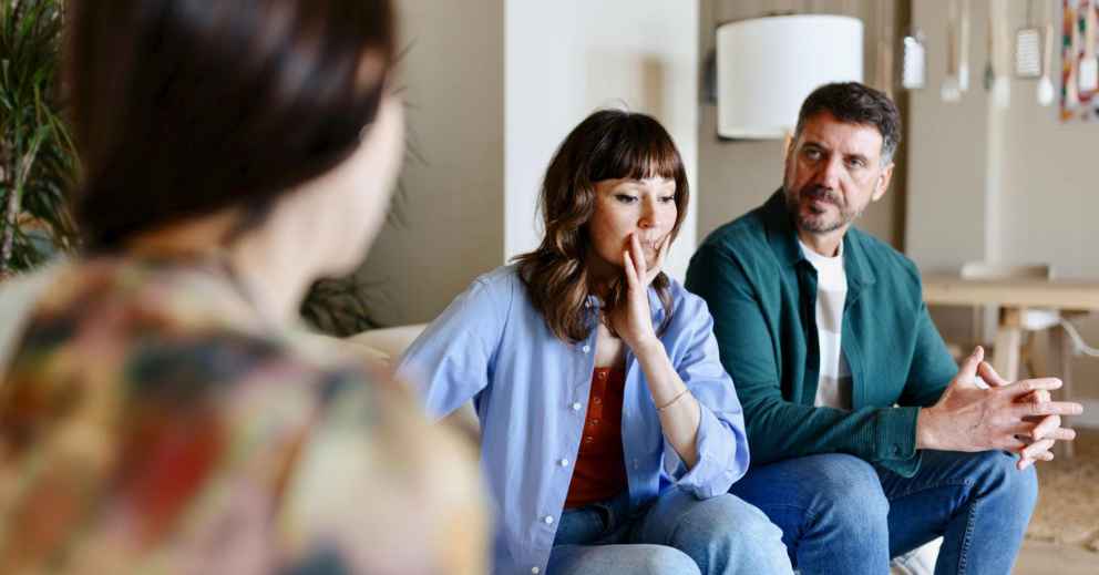 A woman and man discuss parenting arrangements with a third person on the couch.