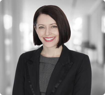 Woman with dark hair in a business suit, smiling—experienced family lawyer in a bright office.