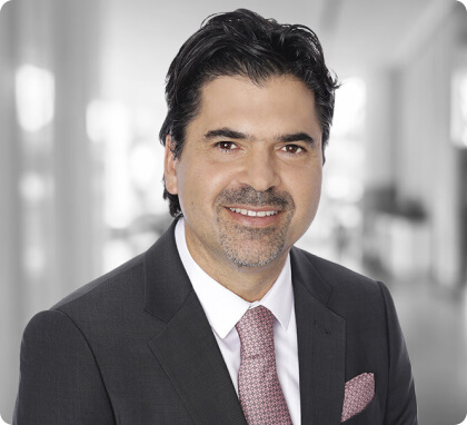 Man in suit and tie smiling in a bright office, representing trusted family lawyers.