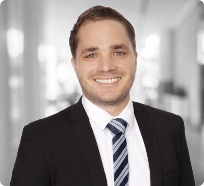 Man in a suit and striped tie, smiling in a bright, modern office—expert family lawyers.