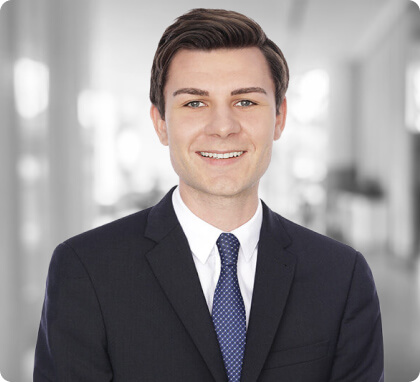 Man in a suit and tie smiling, standing in a bright office—expert family lawyer ready to help.